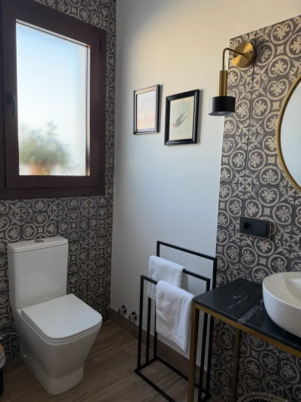 Baño con azulejos grises, inodoro y toallero