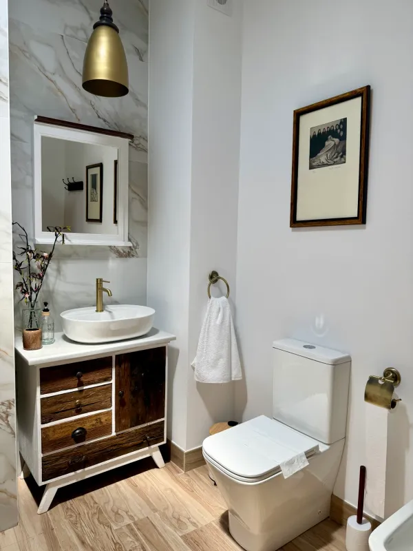 Lavabo con mueble de madera y toallero dorado