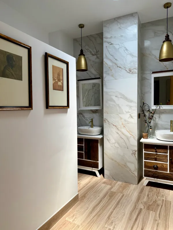 Baño con pared de mármol y mueble de madera