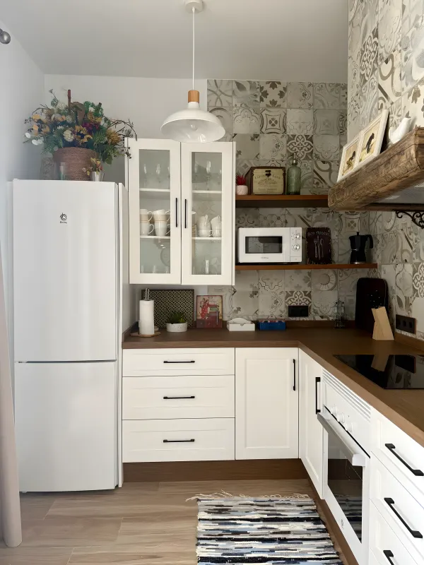 Cocina blanca con azulejos hidráulicos y balda de madera