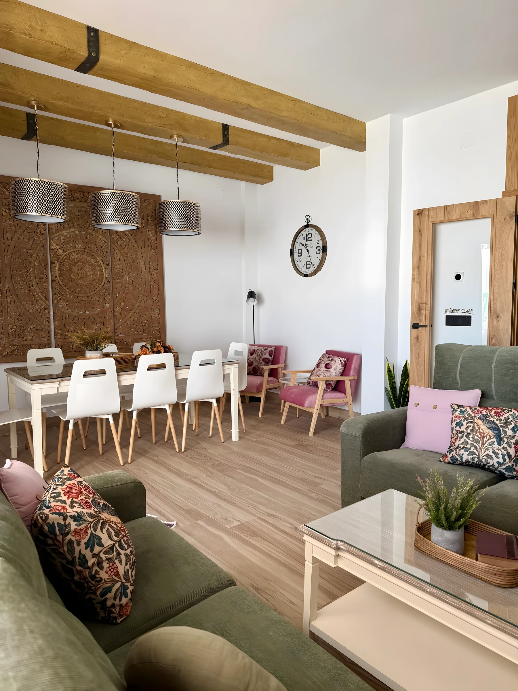 Grande salle à manger avec poutres en bois et fauteuils roses