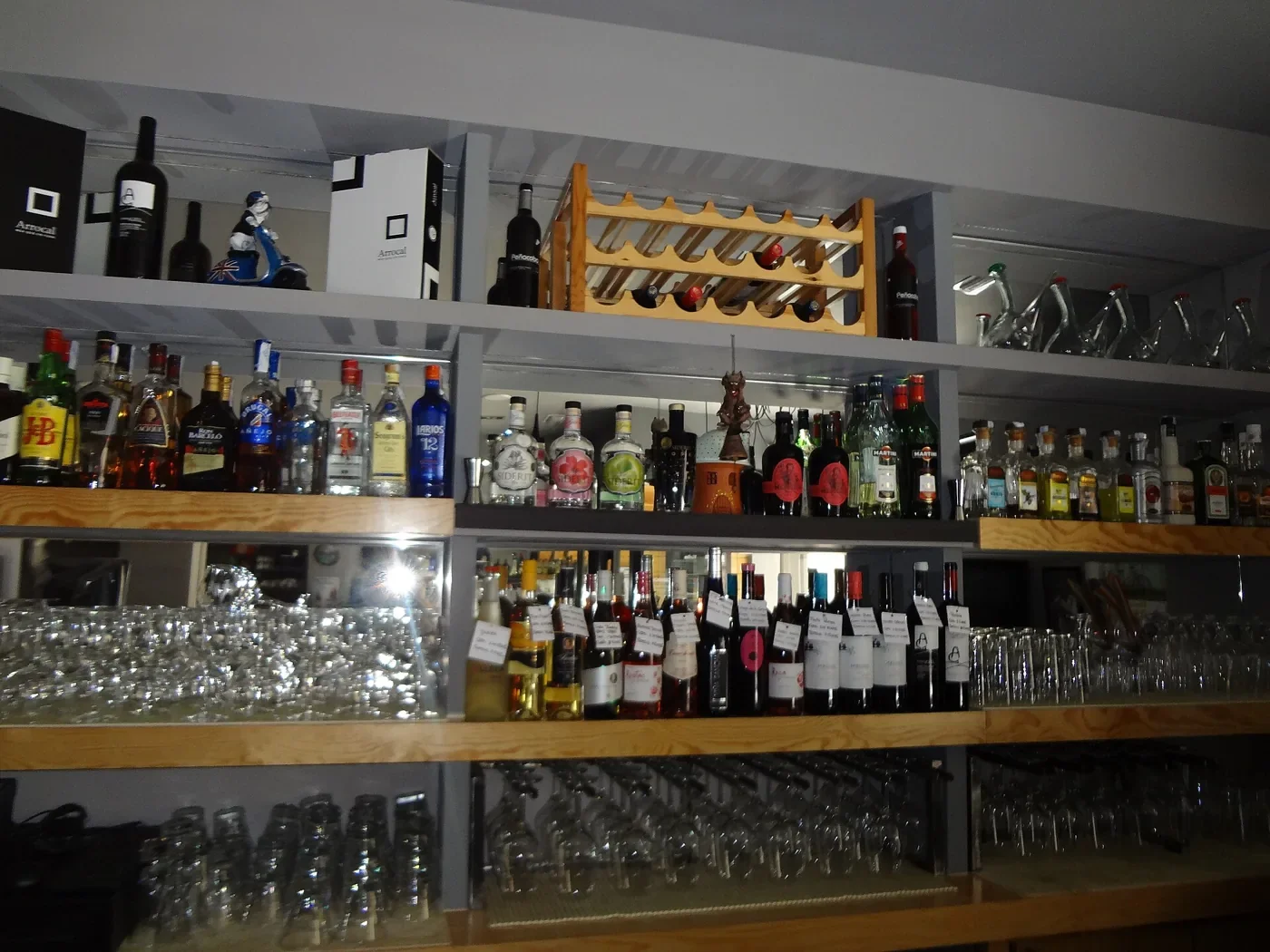 Barra de bar con estantes de botellas y copas