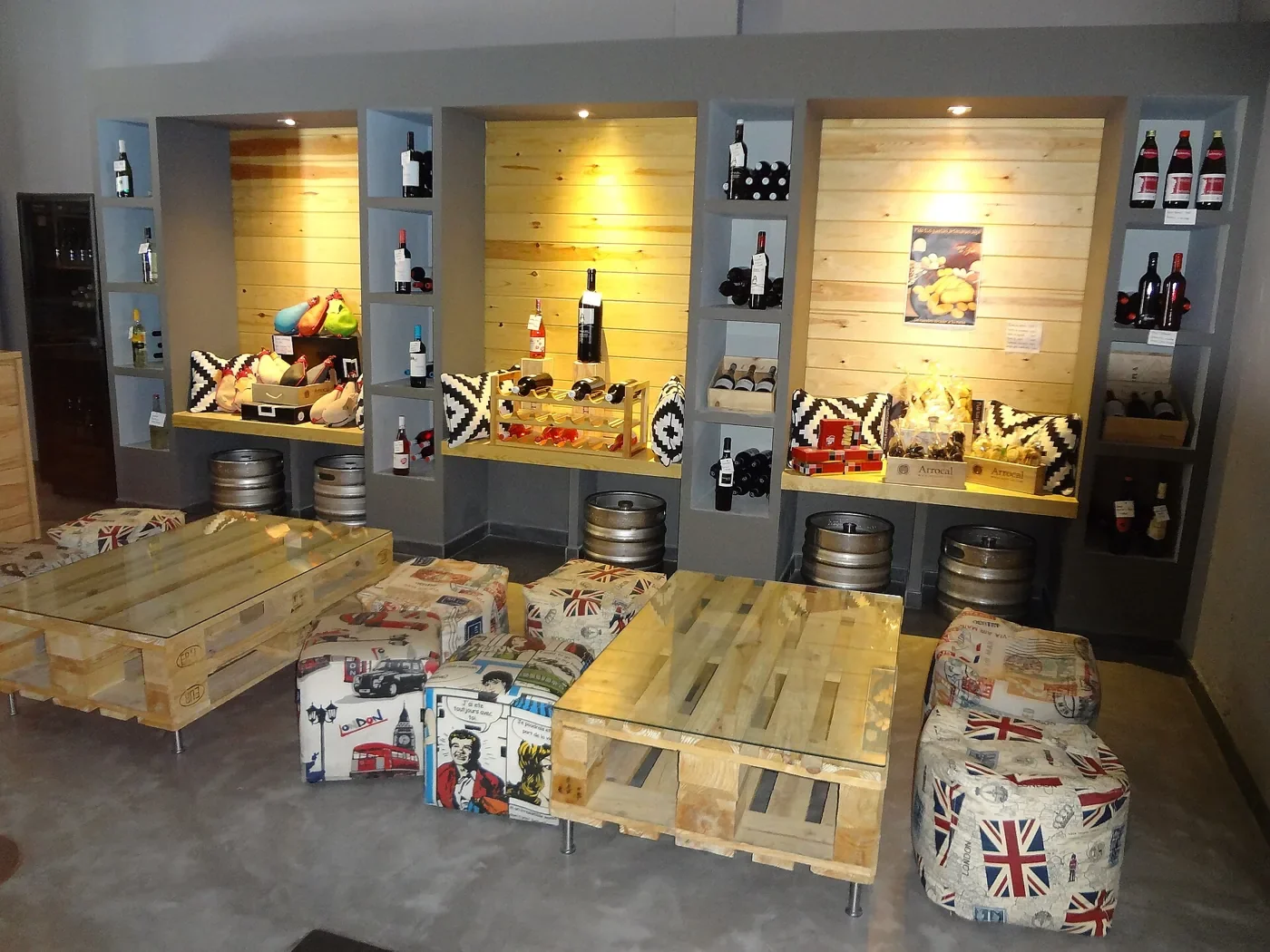 Interior de un bar de tapas con barriles, botellas y mesas de palés