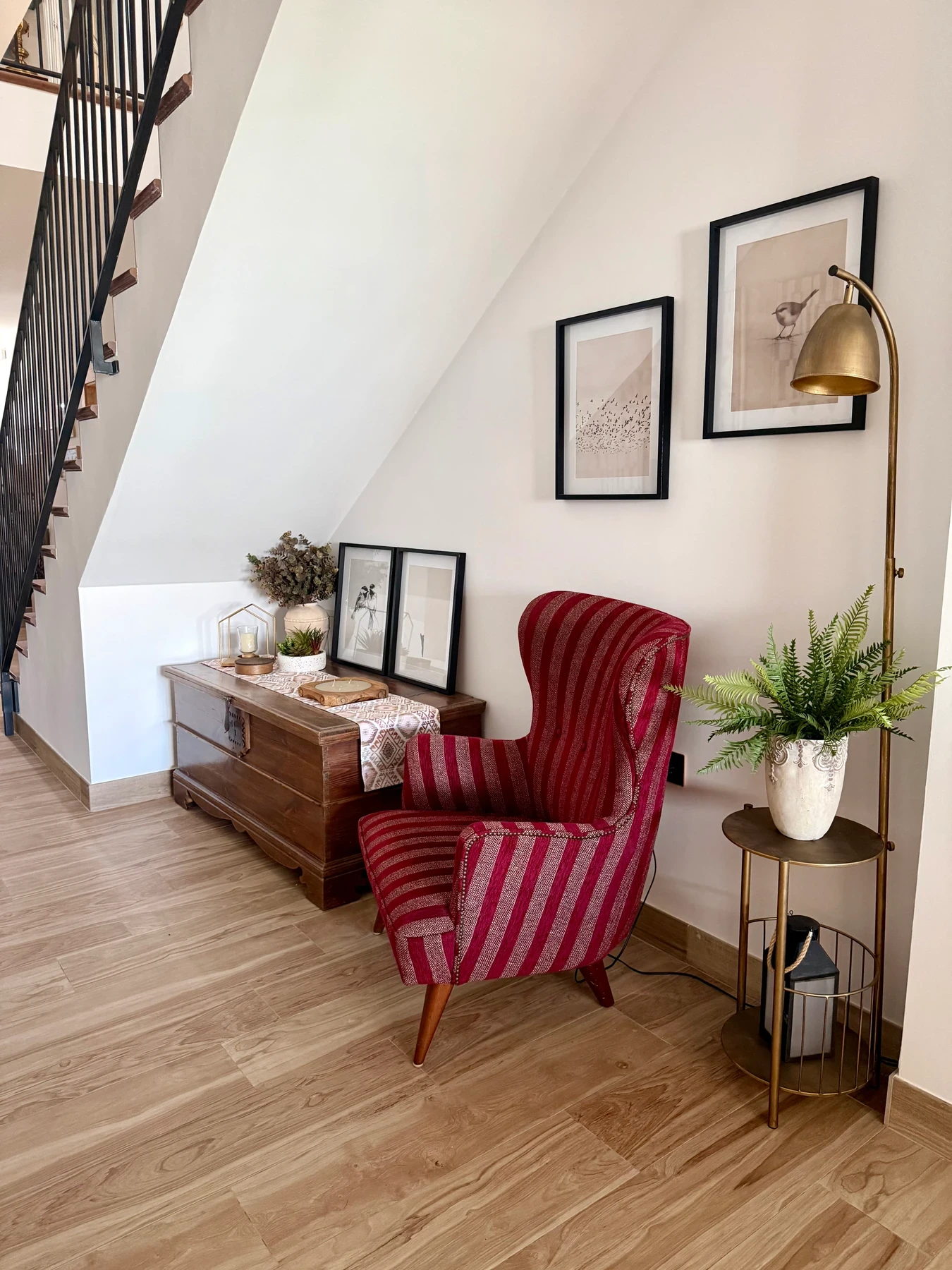 Fauteuil rayé rouge et coffre près de l’escalier