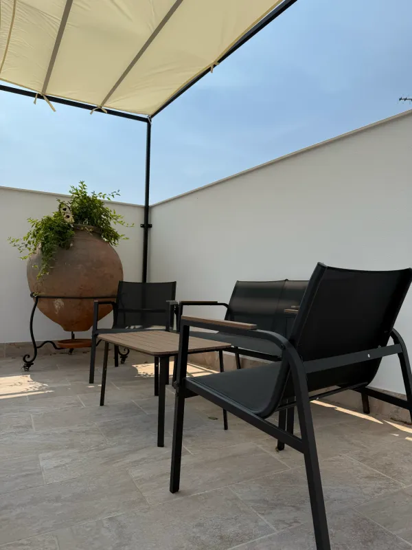 Terraza con pérgola, sillones y una tinaja